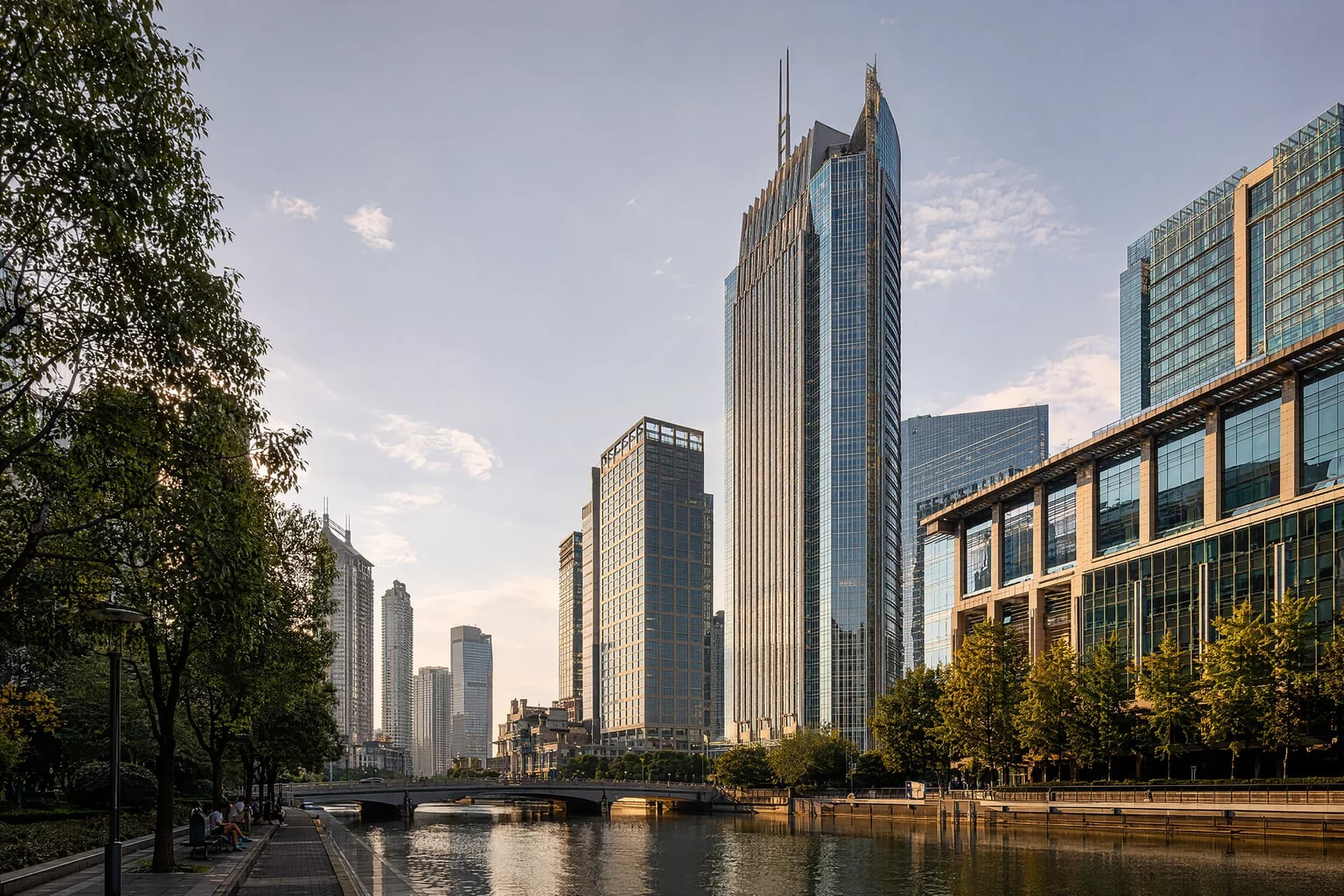 Glass office towers beside a tree-lined waterfront in a fictional modern business district.