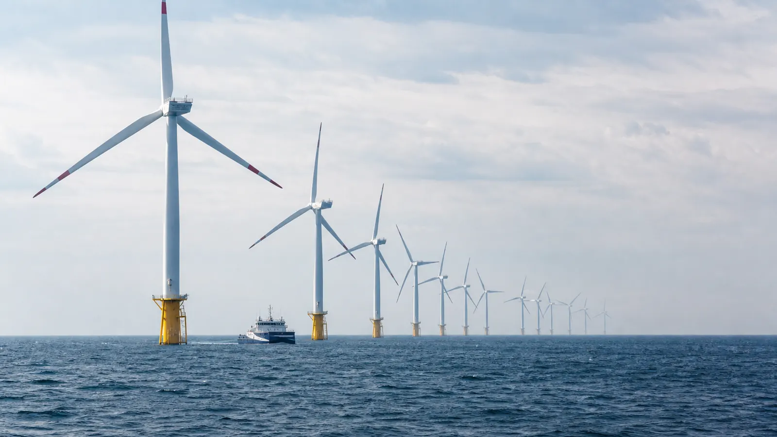 Offshore wind turbines and a service vessel at sea.