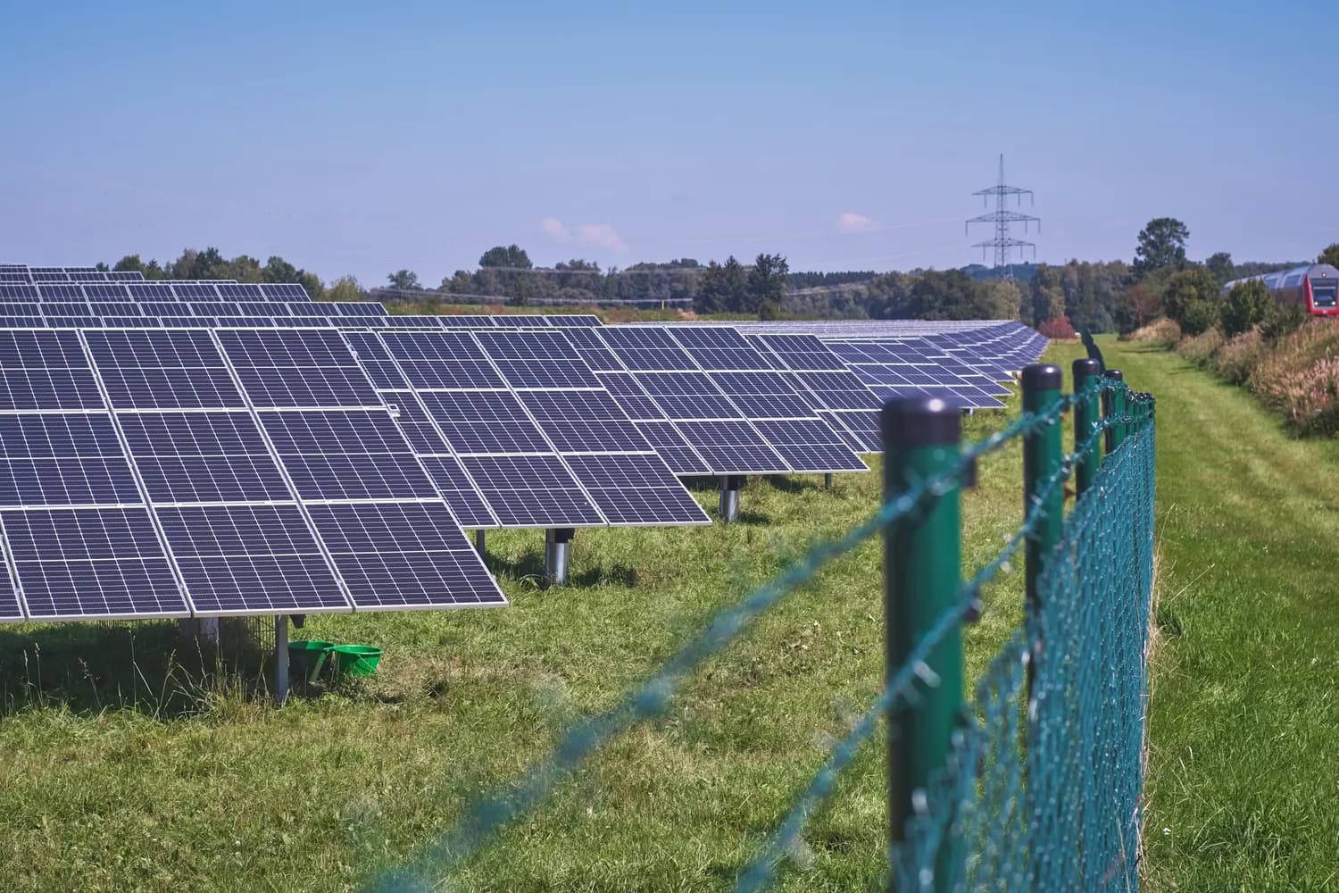 Rows of solar panels beside fenced grid infrastructure, representing land-side renewable-energy project support.
